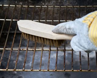 cleaning a bbq grill grate with a wood and wire brush