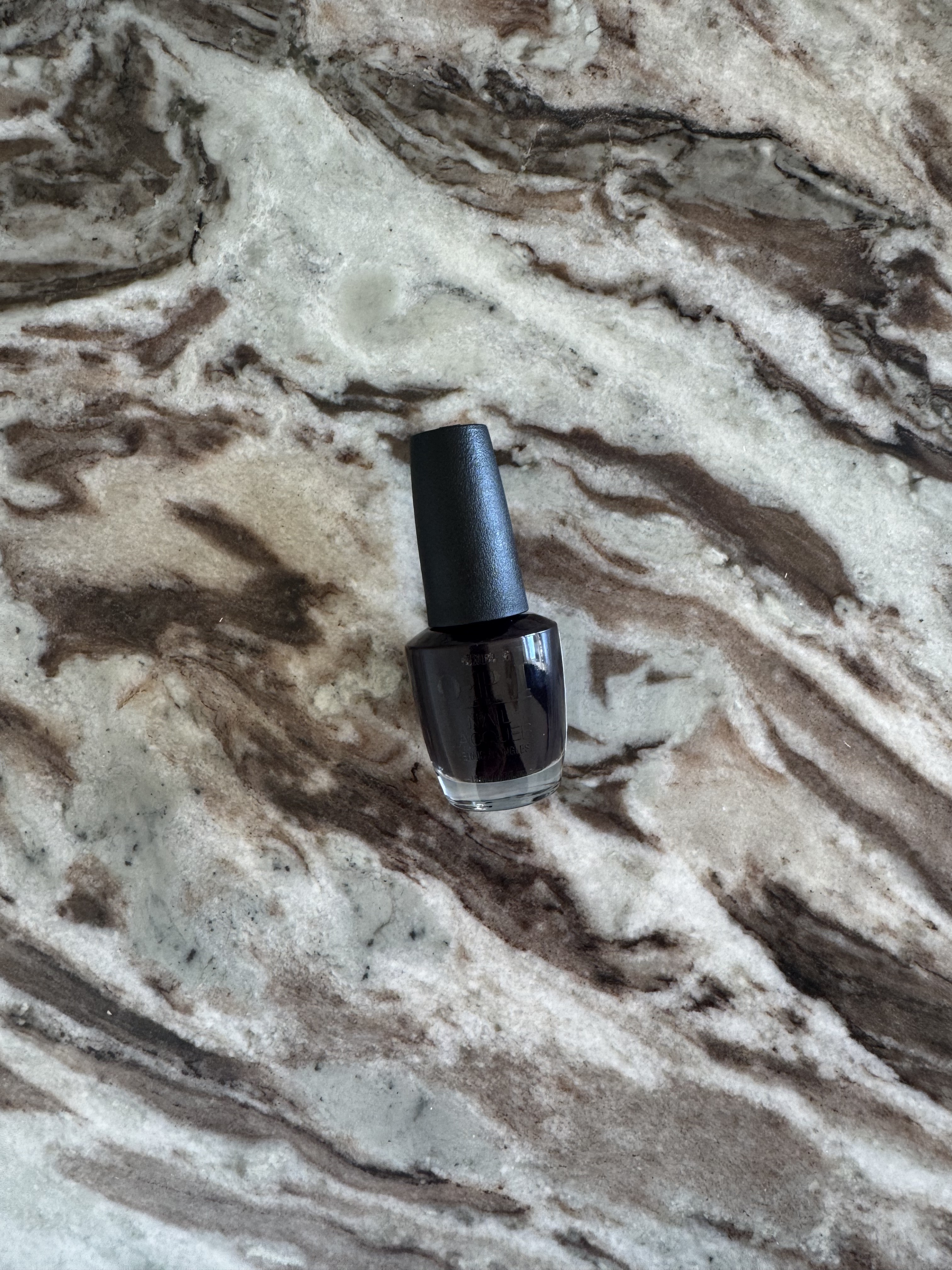 A bottle of OPI Lincoln Park After Dark nail polish on a marbled table