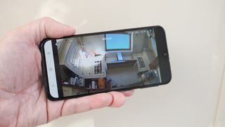 Phone held in a hand showing the app for a Eufy Indoor Cam E220