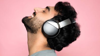 Sonic Lamb hybrid wireless headphones worn by a man against a pink backdrop