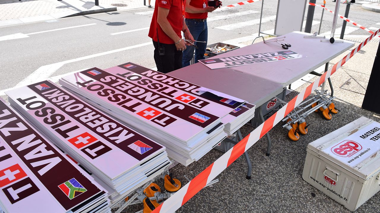 Team cars follow each rider for time trials with a specific name board for each rider attached to the car before setting off