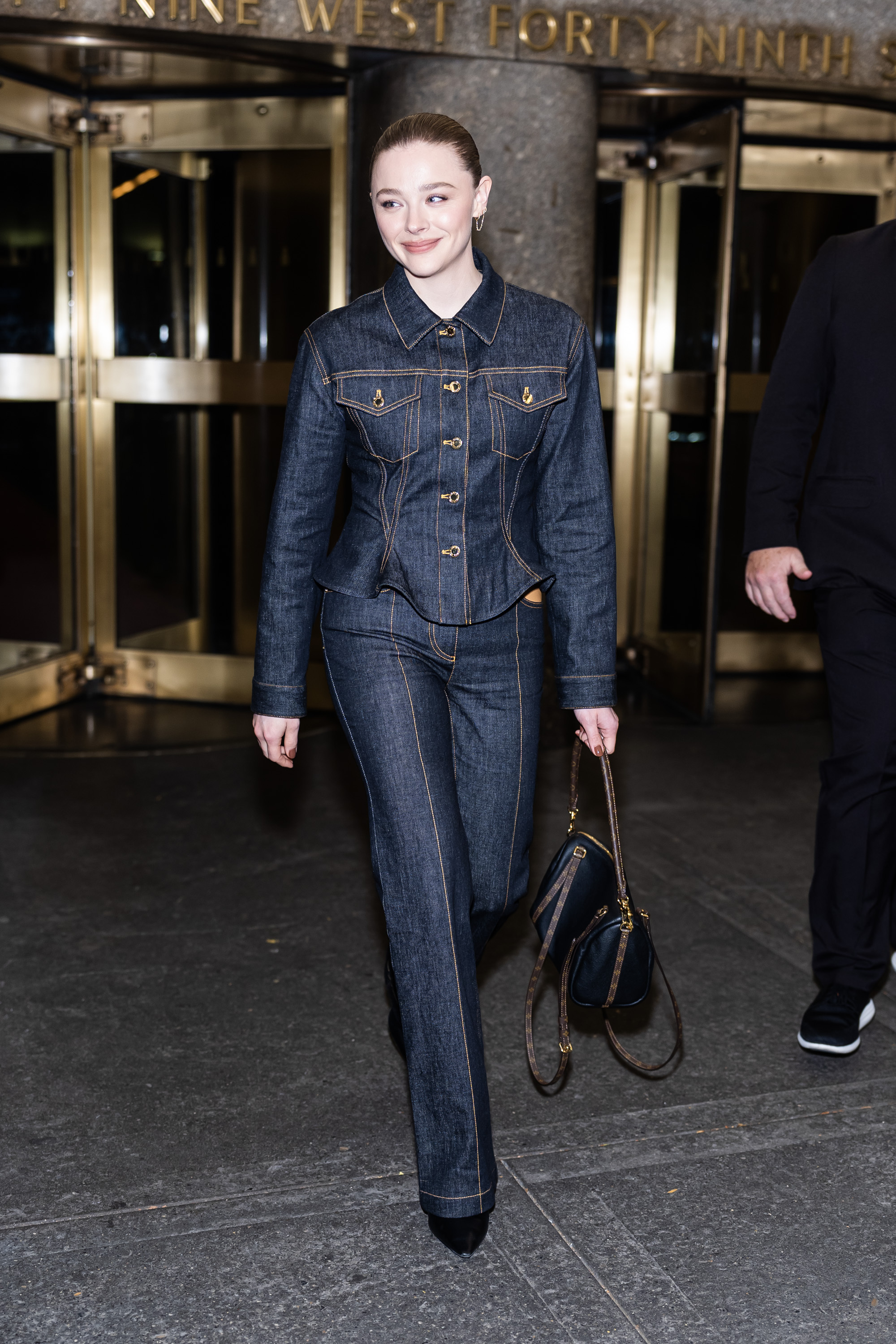 Chloe Grace Moretz wearing dark denim and Louis Vuitton Express bag.