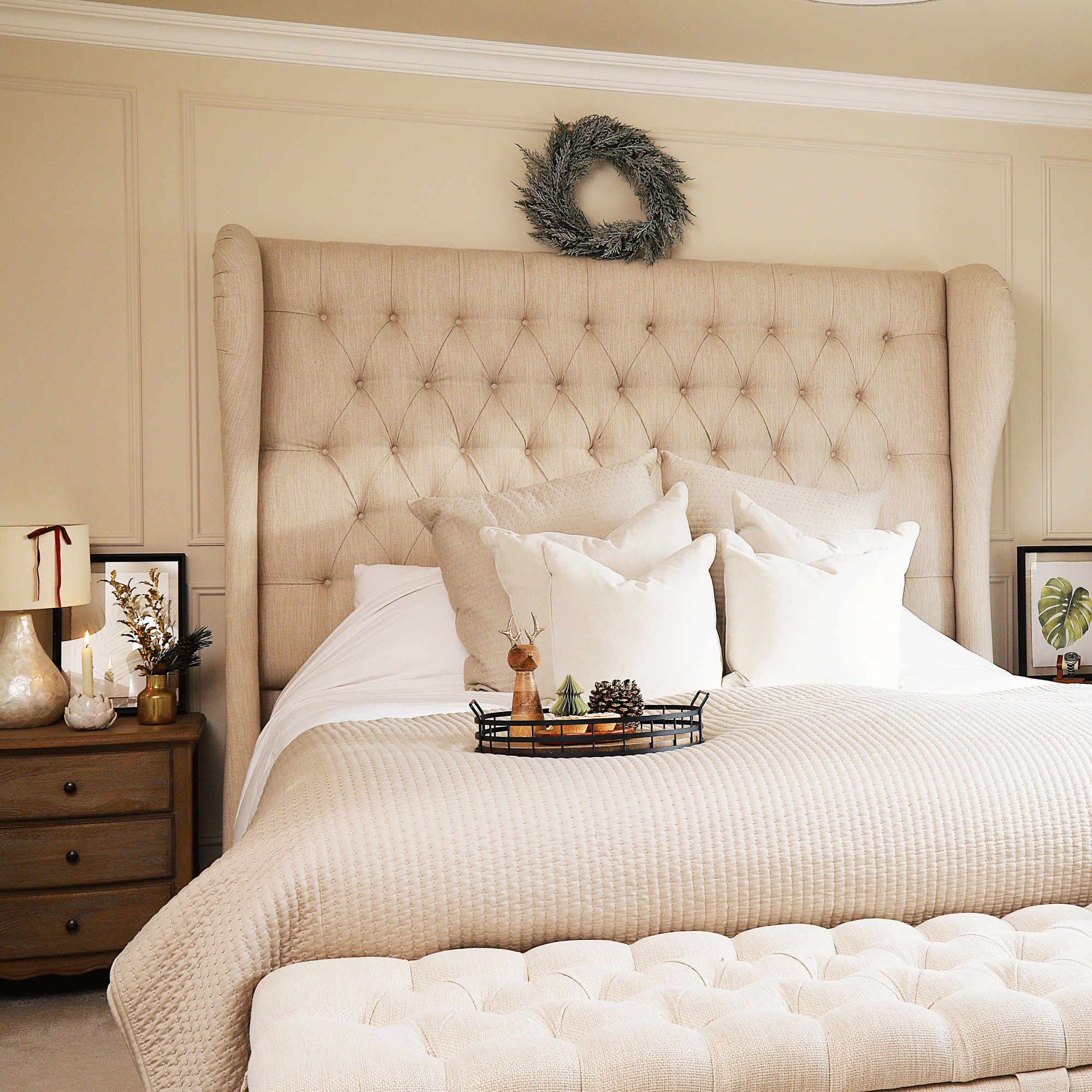 a neutral bedroom with wall panelling decorated for Christmas with presents and candles