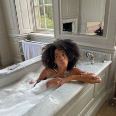 A woman sitting in a marble bath with glowing skin
