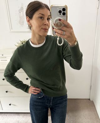 Woman in olive green sweater and jeans.