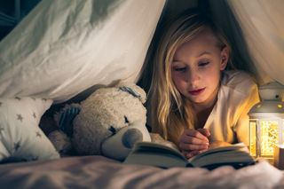 A child reads a book in bed on Christmas Eve