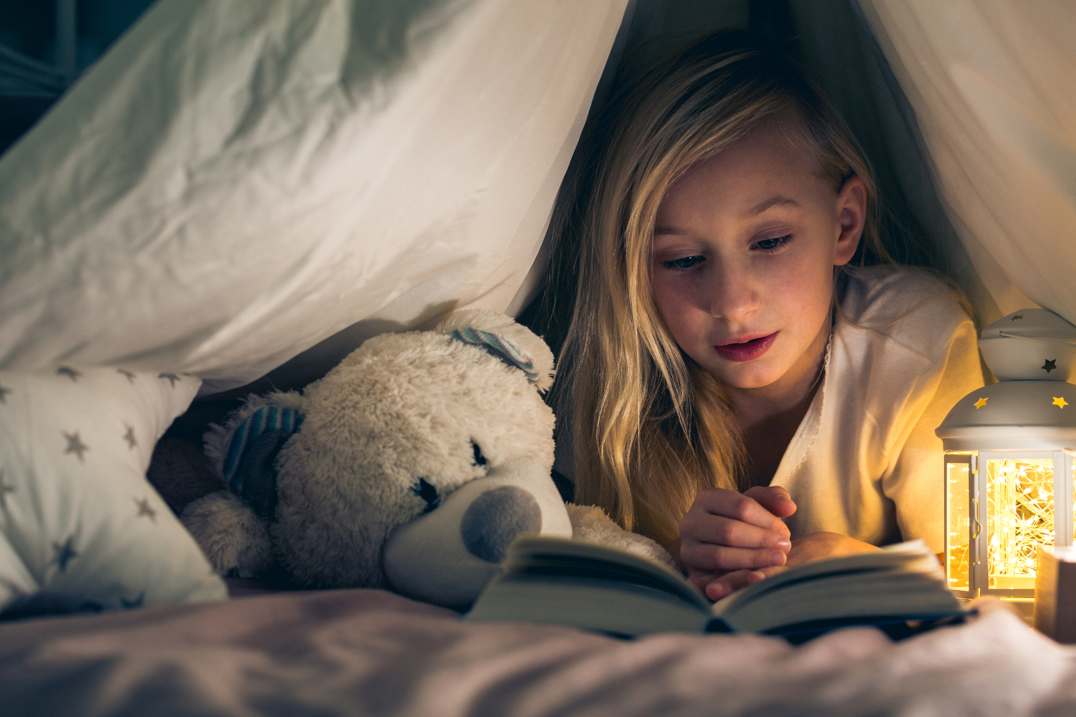 Ein Kind liest an Heiligabend im Bett ein Buch