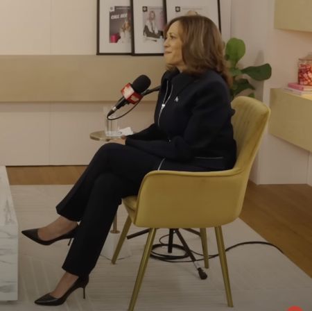 Kamala Harris wearing a black suit sitting in a chair talking on Call Her Daddy podcast