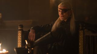 Aemond Targaryen sits next to a fire in House of the Dragon season 2