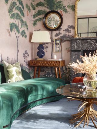 A living room with emerald green sofa and pink walls