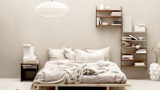 Contemporary wooden bed with white linen and shelves to the right and above bed 