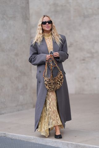 woman wearing lace dress, coat, leopard print bag, and heels