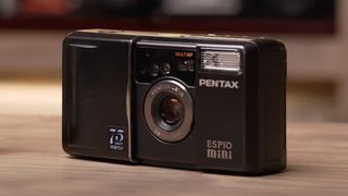A Pentax Espio Mini film camera sitting on a table