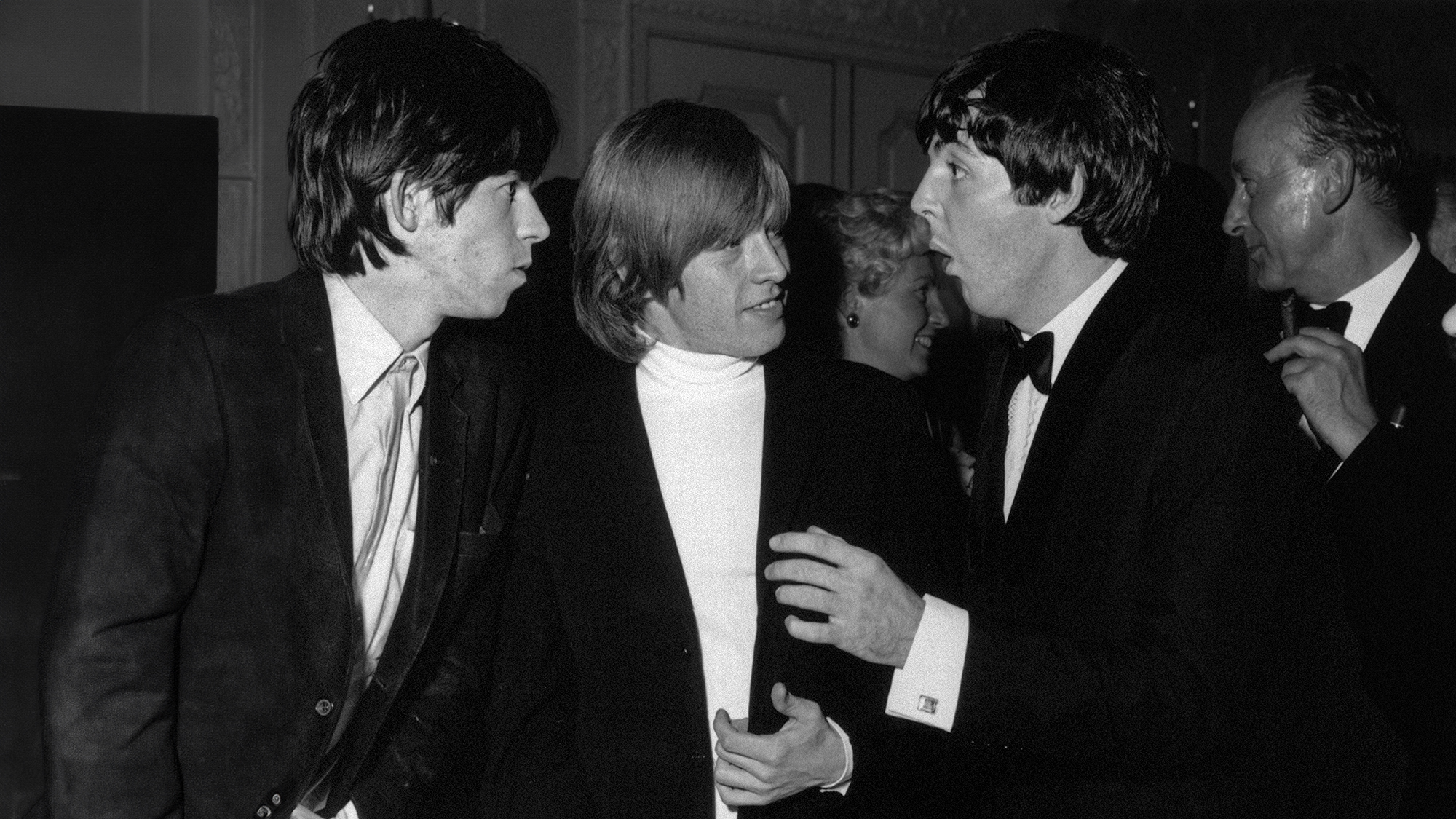 Keith Richards (left) and Brian Jones, chat with Beatle Paul McCartney, in the early hours (7th July) at the Dorchester Hotel London, to celebrate the premiere (6th July) of The Beatles first film, A Hard Day's Night, The Stones were celebrating too, their disc, It's All Over Now, is top of the charts, pictured 2am Tuesday 7th July 1964. 