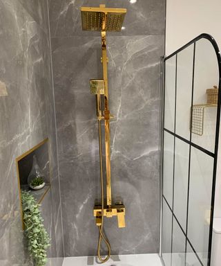 Gilded shower over tub with tiled gray marble effect walls
