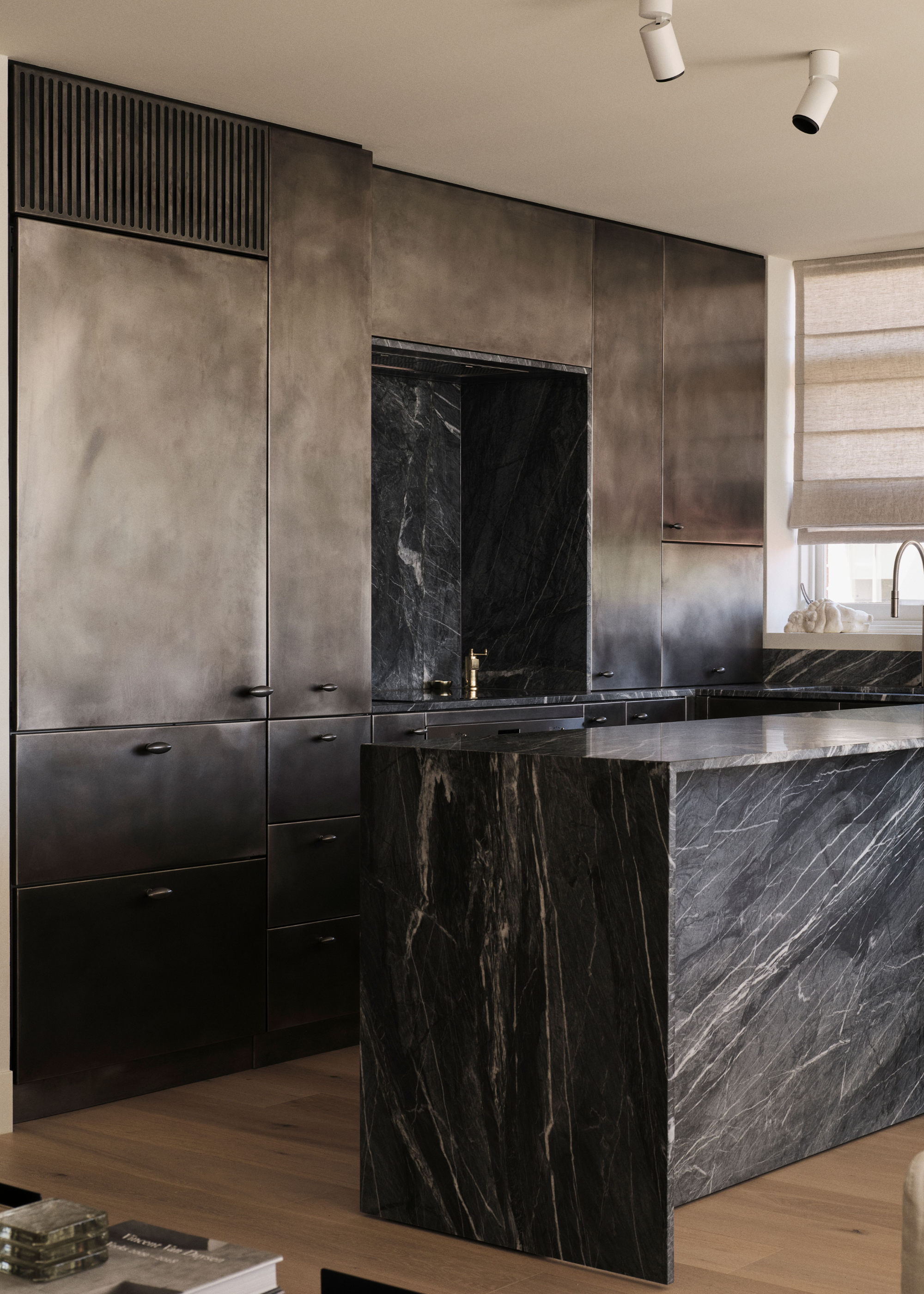 distressed steel cabinets in a kitchen with moody, grey-green marble counters and backsplash
