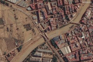 a dirt-filled canal flooding into nearby buildings, as captured by an overhead view