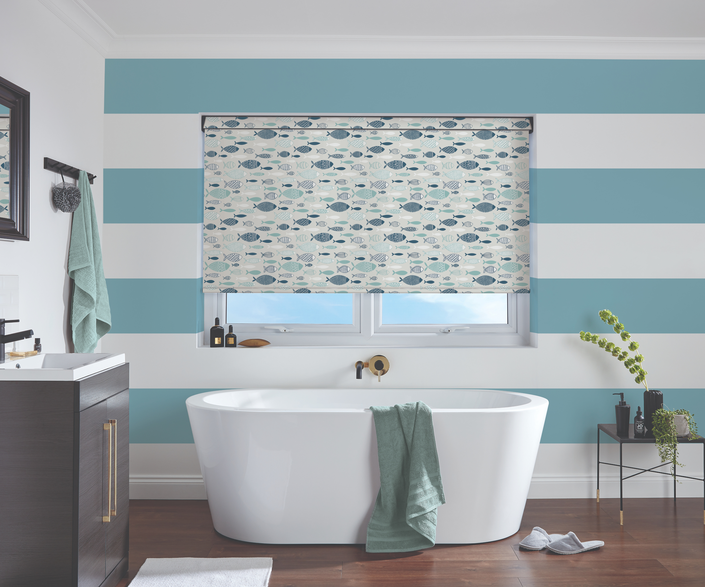 bathroom with blue and white striped wall behind bath and roller blind on window