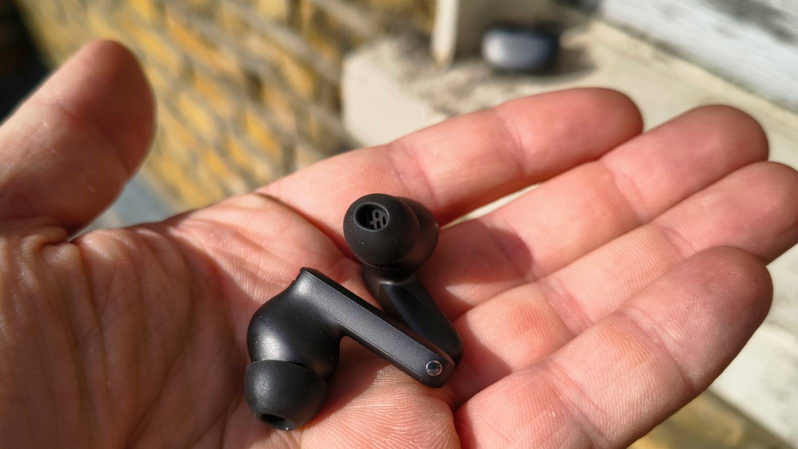 The OnePlus Buds 4 in a man's hands.