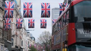 A red London bus and Union Jack flags over Oxford Street in London
