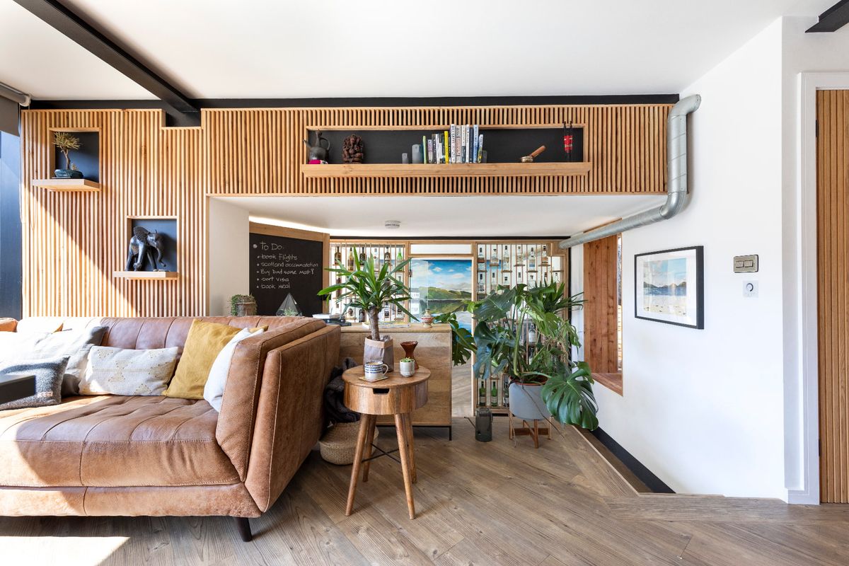 The interior of a tiny home with timber panelling, a sofa and houseplants