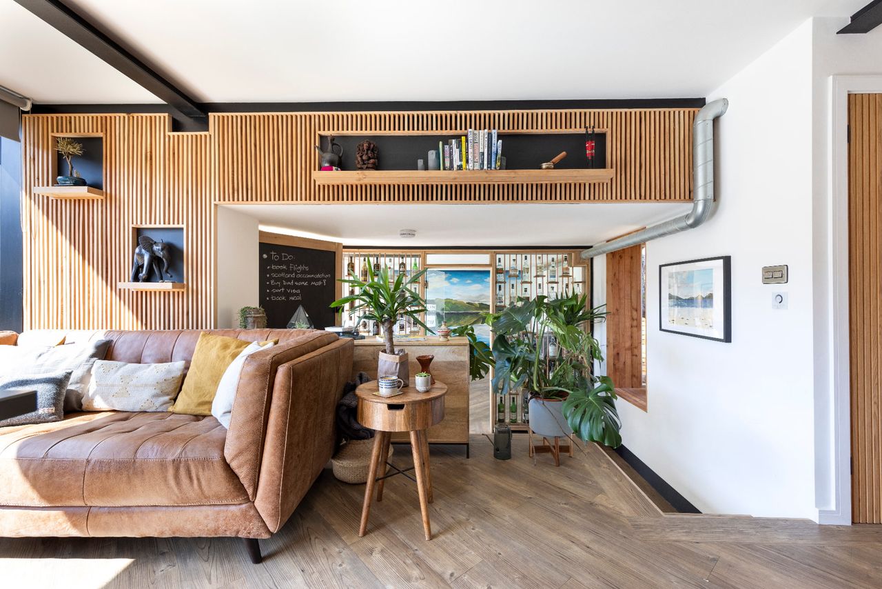 The interior of a tiny home with timber panelling, a sofa and houseplants