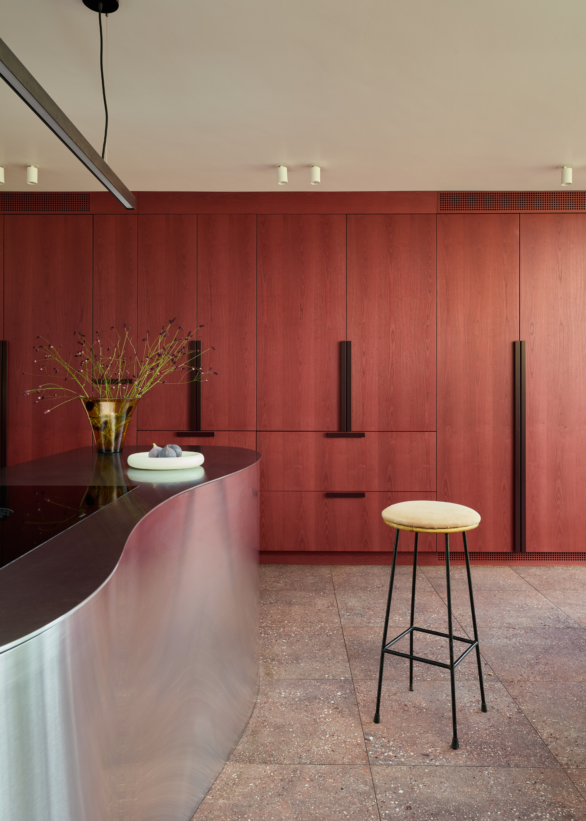 dark red painted wooden cabinet with a stainless steel curved island