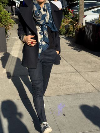 Irene Chen wearing pinstripe trousers with wool coat and large printed scarf.