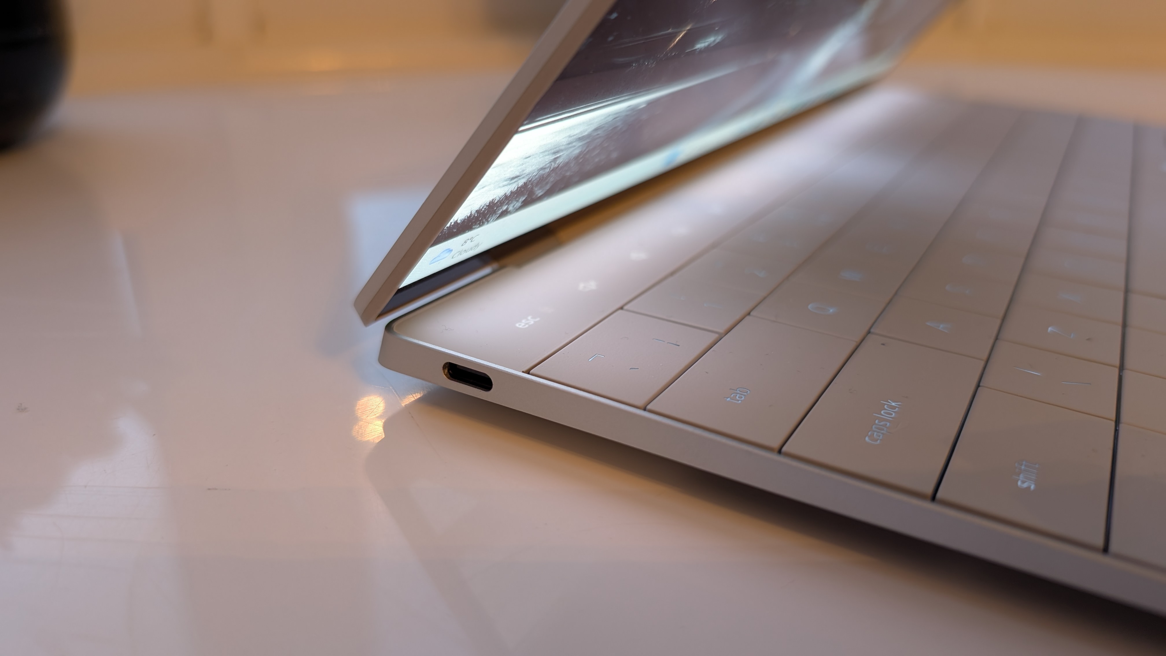 The Dell XPS 13 pictured on a white surface in front of a window with two potted plants.