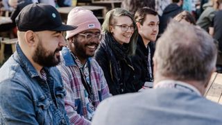 Artists sit around a table smiling