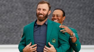 Dustin Johnson receives the Green Jacket from Tiger Woods