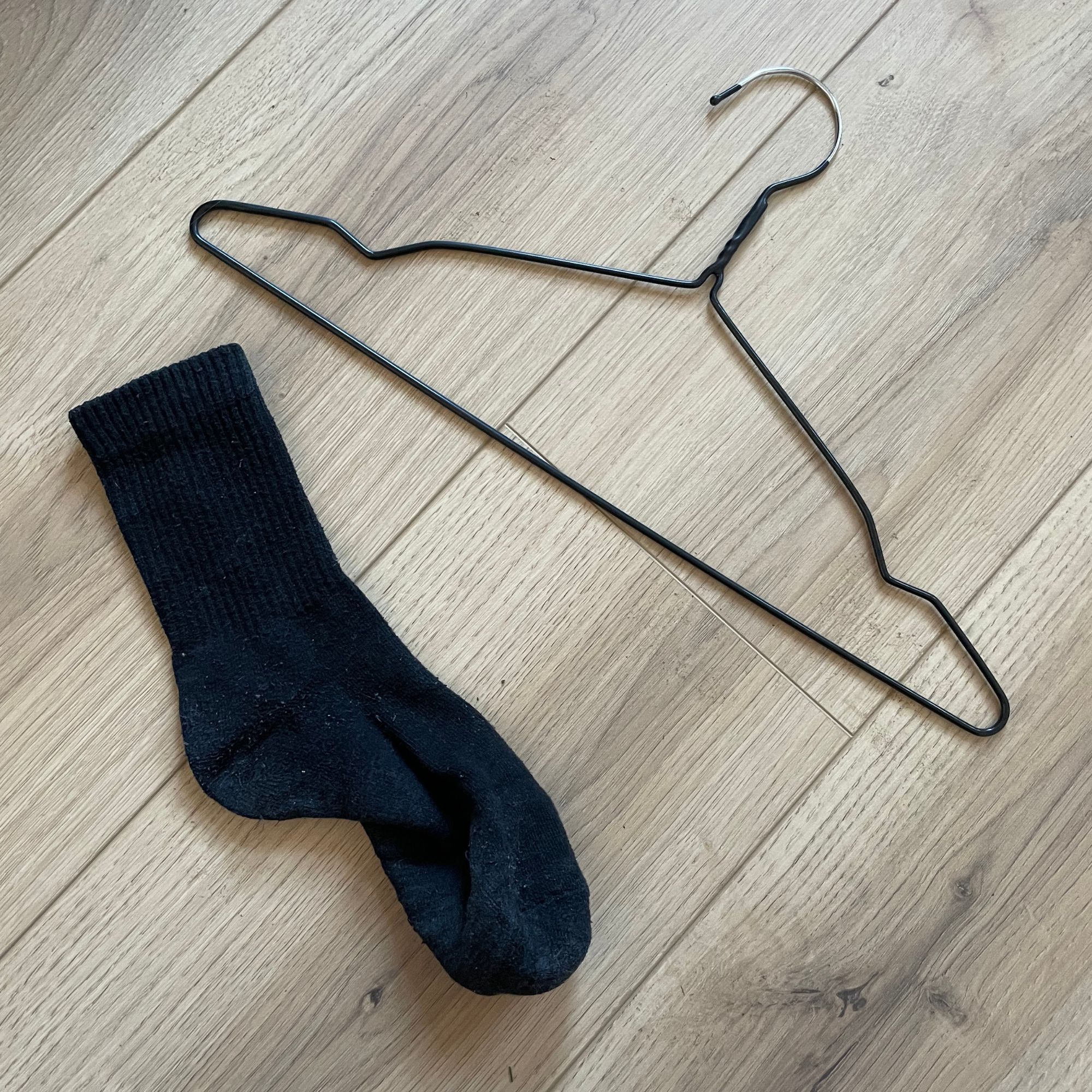 wire hanger and sock laying on wood-effect floor