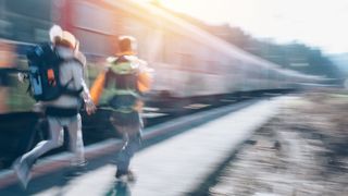Couple wearing heavy backpacks running alongside train
