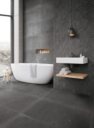 grey toned bathroom in space with open windows, freestanding bath and wall mounted sink and storage