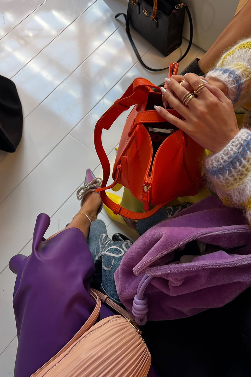 A woman wearing a purple satin skirt, and purple textured handbag