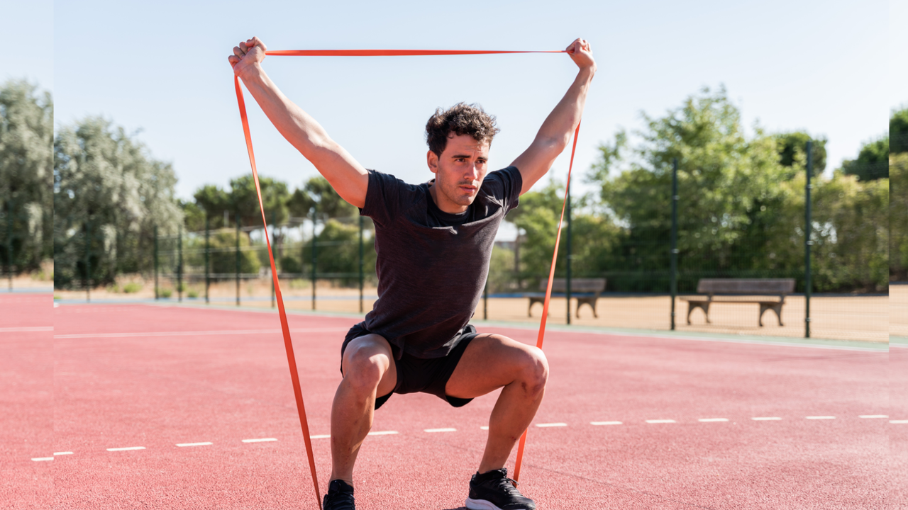 man doing squats with a loop resistance band