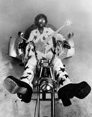 Bootsy Collins on a motorbike, in shades, carry a star-shaped bass