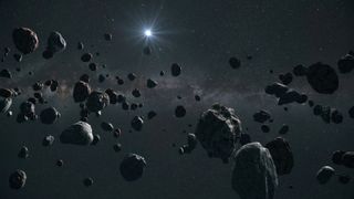 A large group of asteroids with the sun in the distance