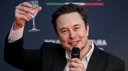 Elon Musk holds a glass of wine.