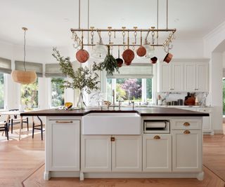 kitchen with white cabinets and hanging pans over island with black countertop