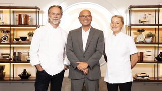 Marcus Wareing in chefs' whites, Gregg Wallace in a dark suit and white shirt and Anna Haugh in chefs' whites stand in a kitchen in MasterChef: The Professionals