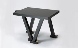 A modern table with asymmetrical legs in black lacquerware.