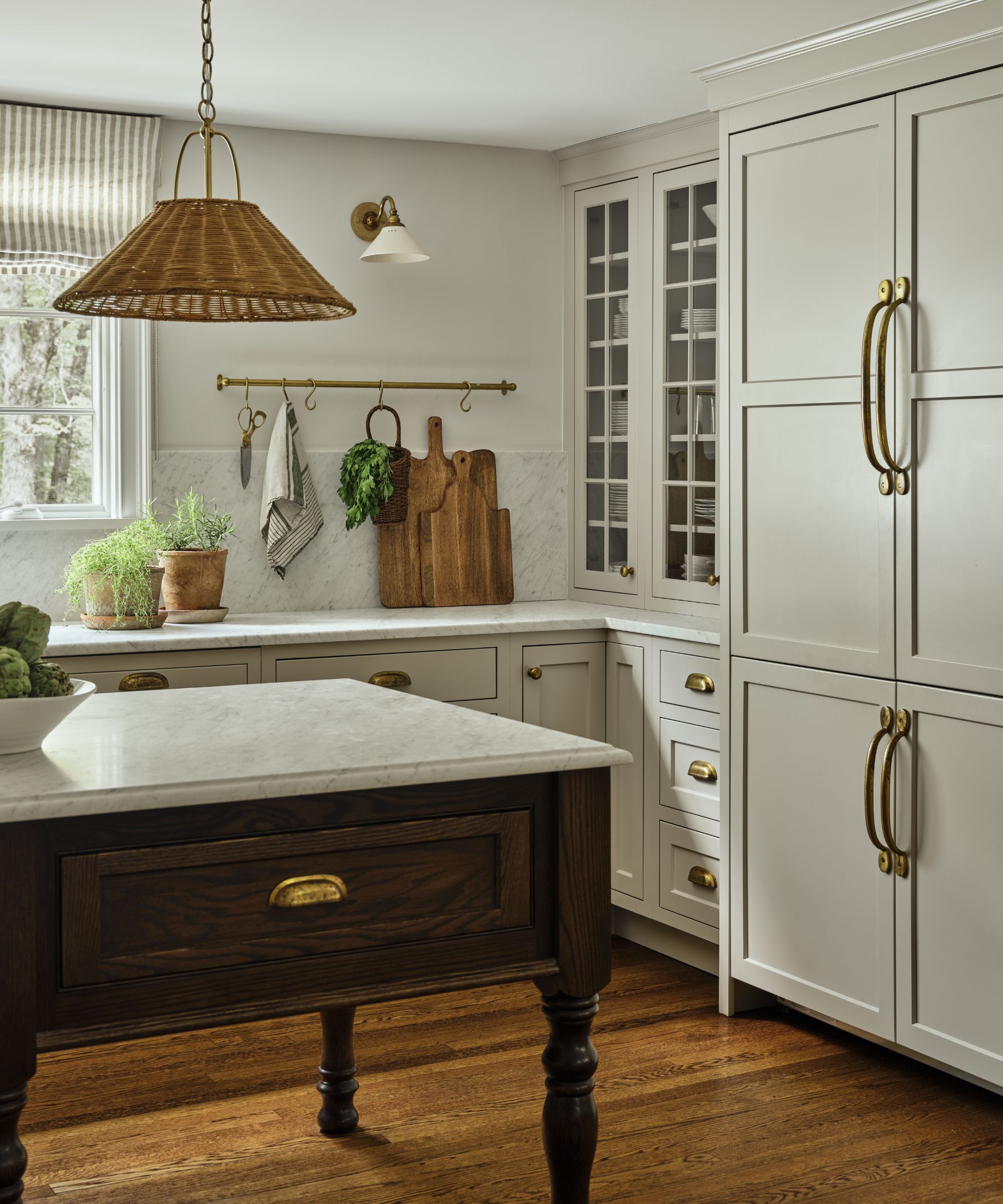 a warm neutral english country style kitchen with open shelving and marble counters and a dark wooden island