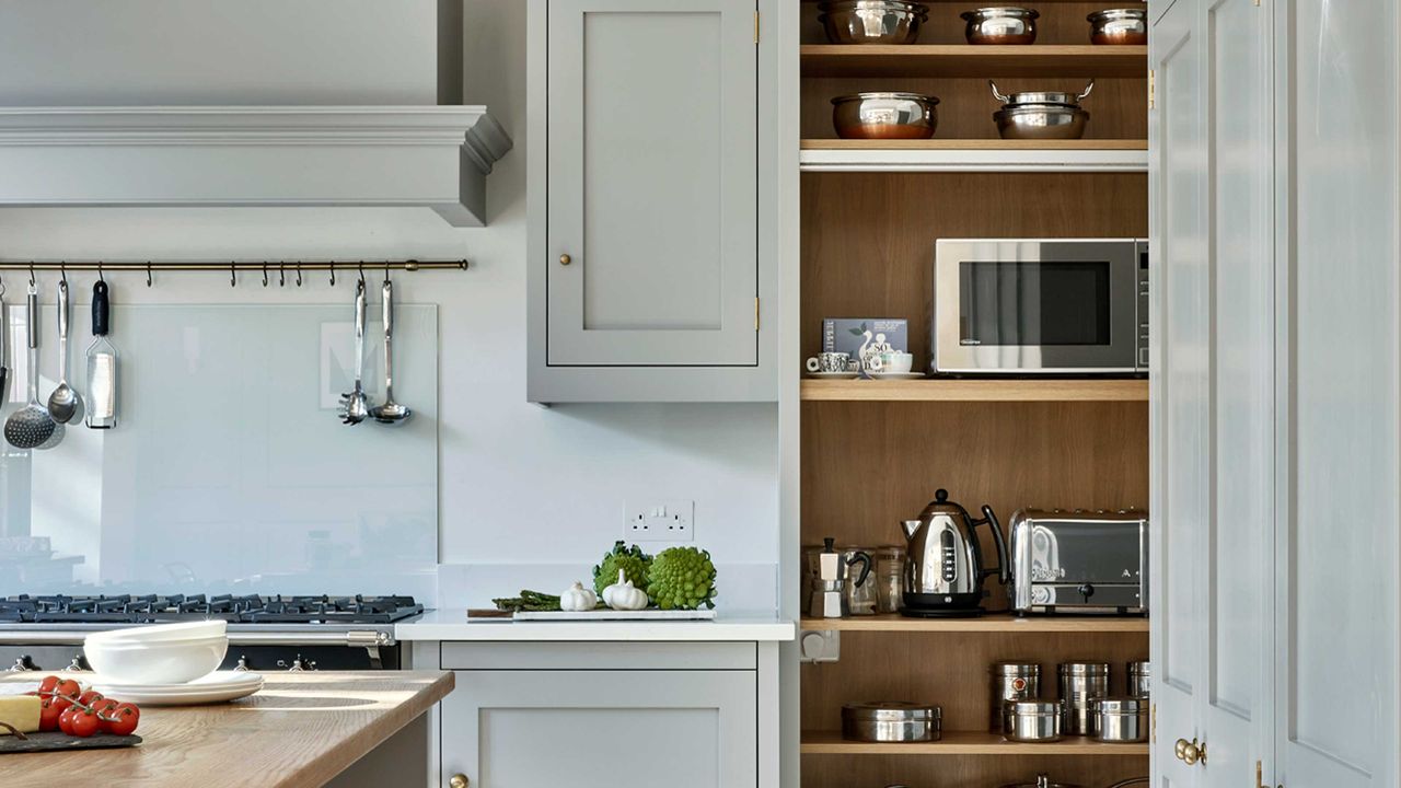 Blue kitchen with cupboard filled with appliances including microwave oven