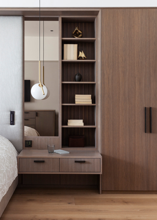 A bedroom with a built-in nightstand and attached wardrobe