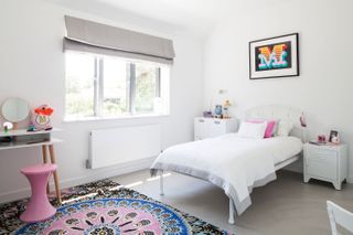 kids bedroom with white bedding, white walls and a statement boho rug