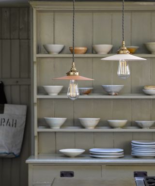 A kitchen lighting idea by Pooky using their Cecilia pendant lights in front of a cream dresser with plates and bowls