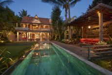 Traditional wooden house at dusk with Pergola sitting area, luxury property concept