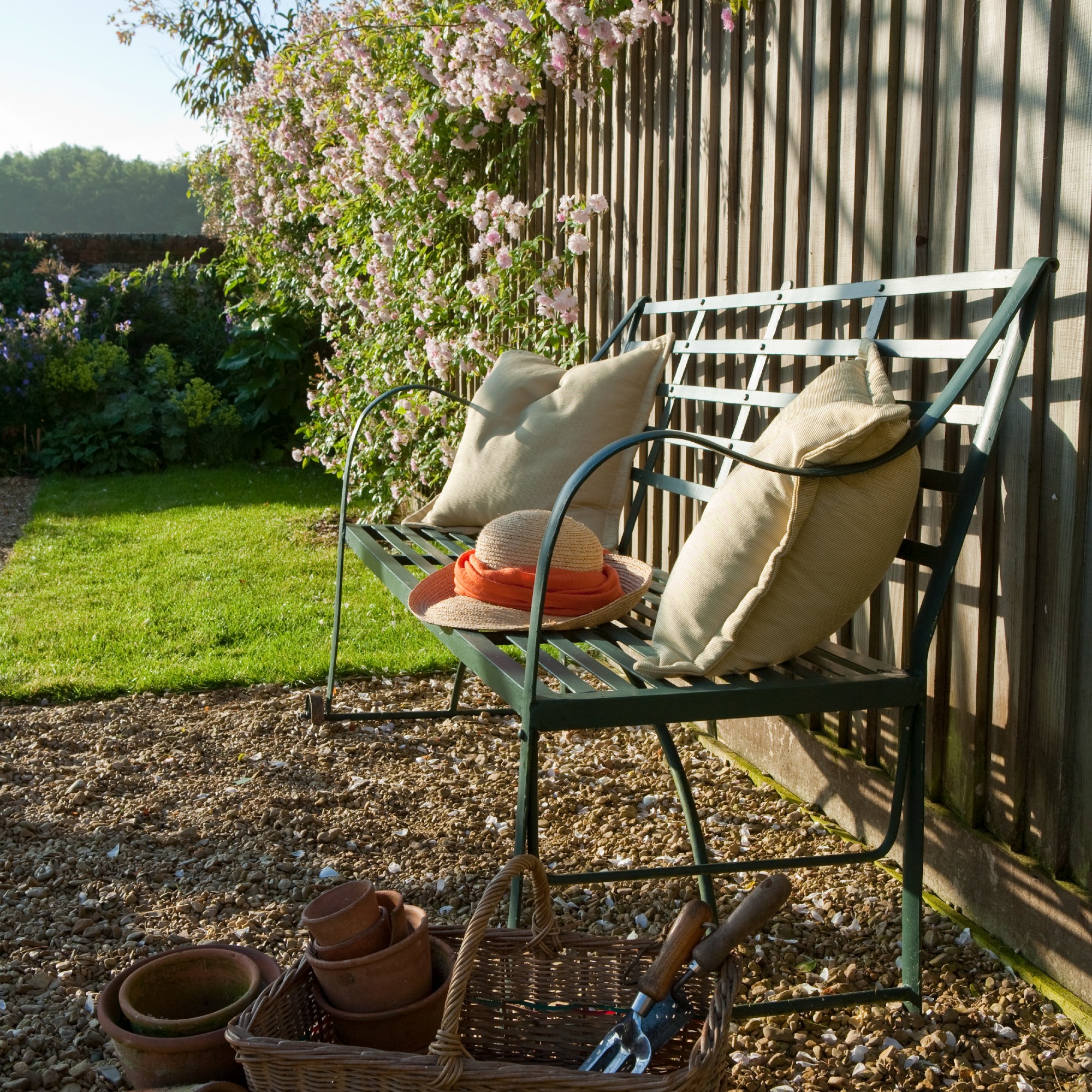 A green metal garden bench with gardening supplies