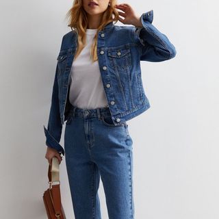 Cropped image of woman wearing denim jacket and jeans 